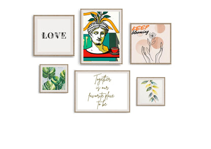 The gallery wall features six framed artworks in natural wood frames, including: An abstract portrait of a classical bust in vibrant yellow, red, and turquoise. Minimalist black typography stating "LOVE." A hand-drawn sketch of hands holding a flower with "KEEP blooming." A square print of lush green tropical leaves. A small print of stylized yellow and green leaves. Flowing gold calligraphy stating "Together is our favourite place to be.".Wall art by wall and more
