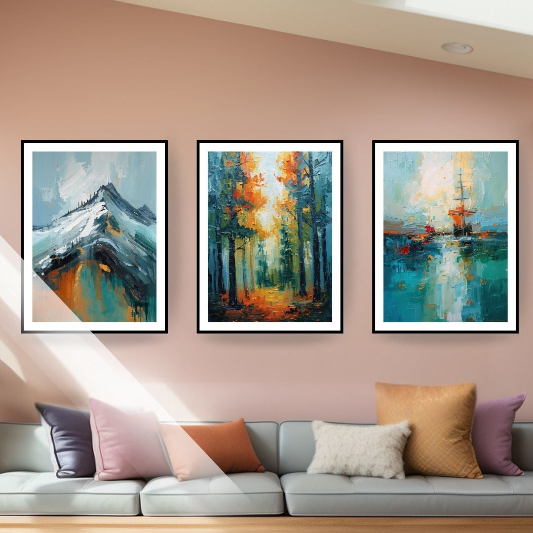 Three framed abstract nature paintings hanging on a soft pink wall above a light grey sofa. The triptych features textured, impasto-style brushstrokes depicting a blue mountain peak, an autumn forest with sunlight, and a sailboat at sea. The couch is adorned with throw pillows in purple, pink, rust, cream, and mustard yellow that coordinate with the artwork's color palette.