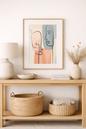 Minimalist framed abstract line art with soft neutral and terracotta tones displayed above a console